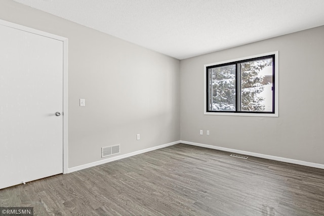 spare room featuring a textured ceiling and hardwood / wood-style flooring