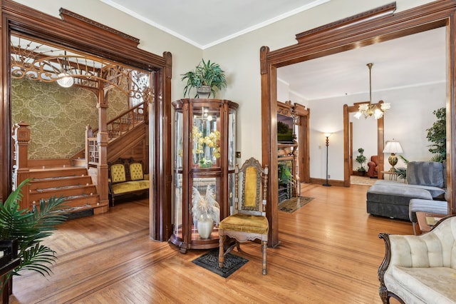 living area featuring light hardwood / wood-style flooring, ornamental molding, and an inviting chandelier