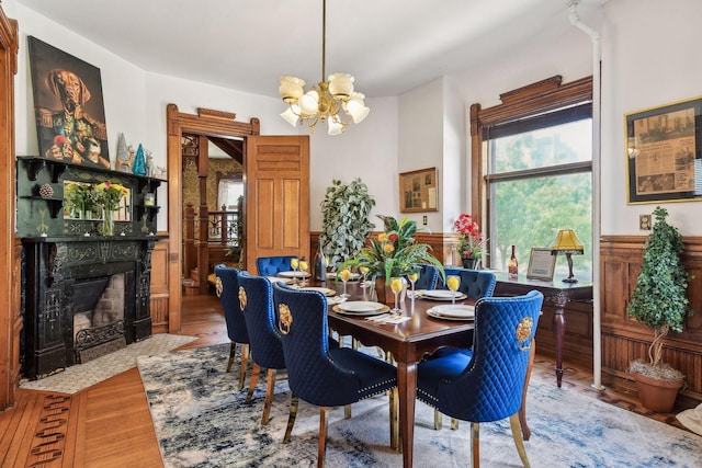 dining area featuring a chandelier, light hardwood / wood-style flooring, and a stone fireplace