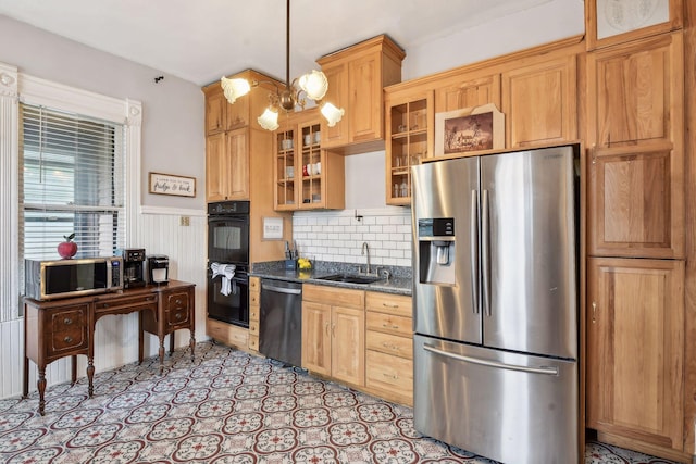 kitchen featuring sink, stainless steel appliances, an inviting chandelier, dark stone counters, and decorative light fixtures