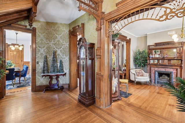 corridor with hardwood / wood-style floors, a chandelier, and ornamental molding