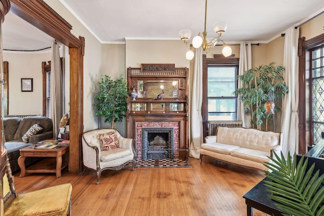 sitting room with a notable chandelier, light wood-type flooring, and ornamental molding