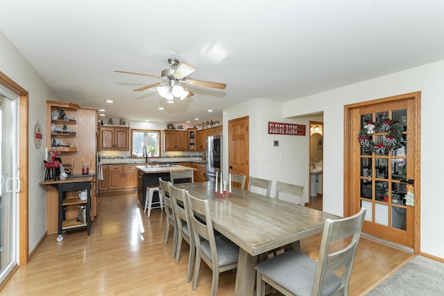 dining space with ceiling fan, sink, and light wood-type flooring