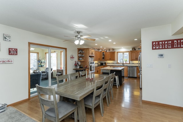 dining area featuring sink, light hardwood / wood-style floors, and ceiling fan