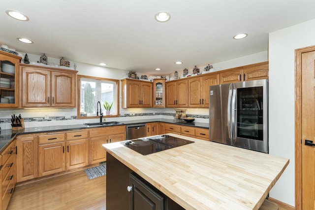 kitchen with appliances with stainless steel finishes, wood counters, sink, backsplash, and light wood-type flooring