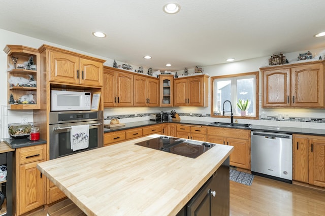 kitchen featuring wood counters, sink, tasteful backsplash, light hardwood / wood-style flooring, and stainless steel appliances