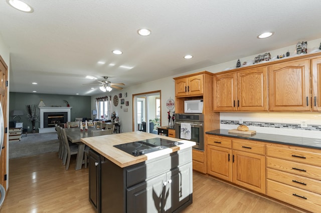 kitchen featuring wooden counters, backsplash, black electric stovetop, oven, and light wood-type flooring