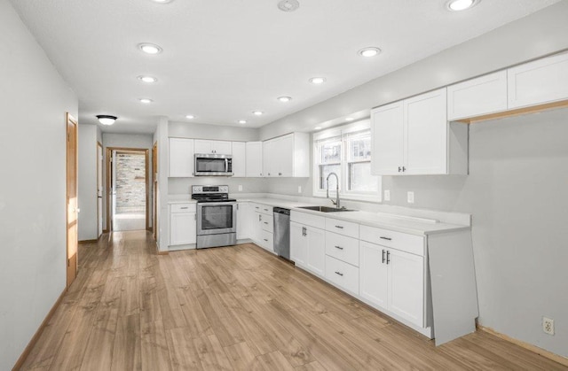 kitchen with white cabinets, light hardwood / wood-style floors, sink, and appliances with stainless steel finishes