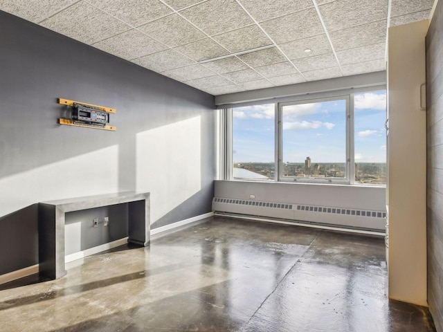 spare room featuring a paneled ceiling and a baseboard heating unit