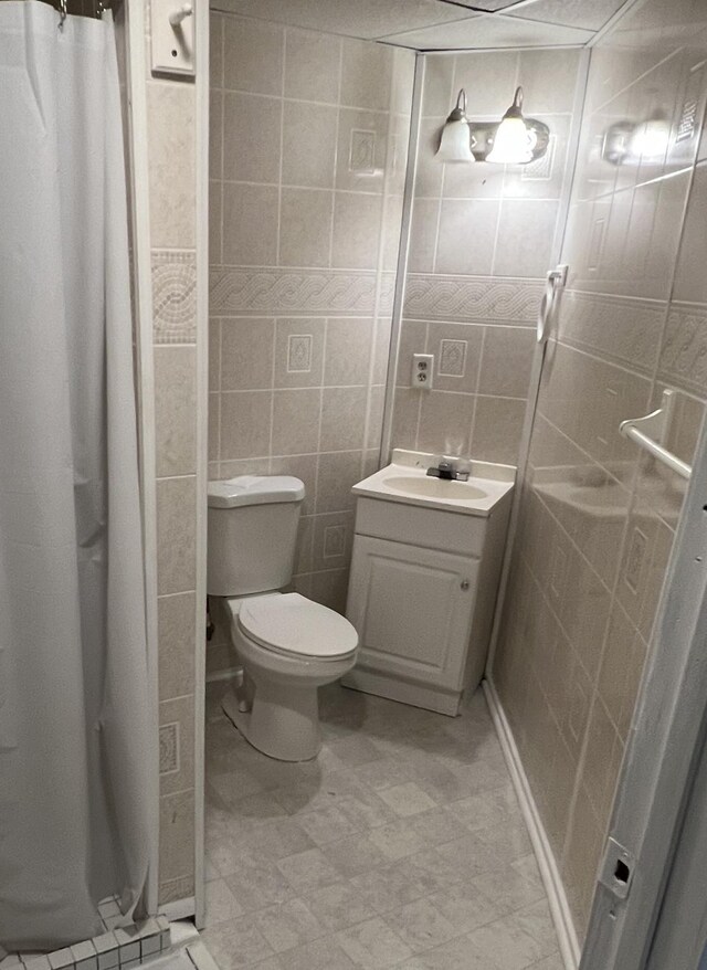 bathroom with a shower with shower curtain, vanity, toilet, and tile walls