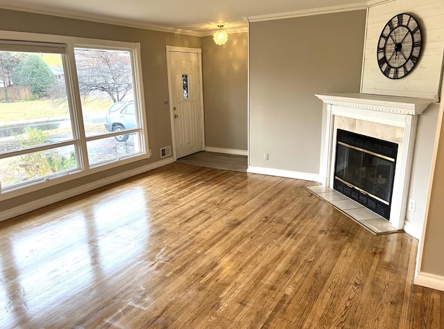 unfurnished living room with a tile fireplace, hardwood / wood-style floors, and ornamental molding