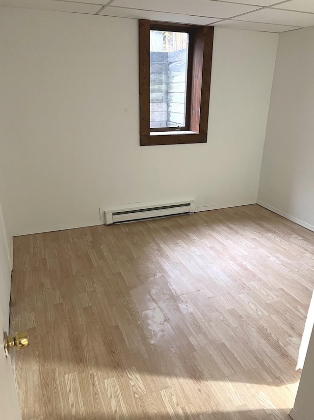 spare room featuring baseboard heating, a paneled ceiling, and light hardwood / wood-style flooring