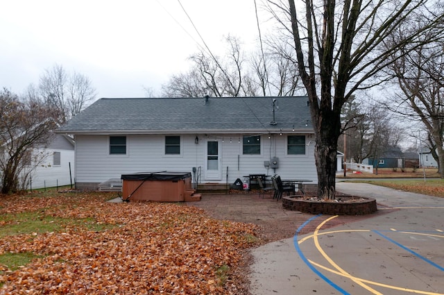 back of property with basketball court and a hot tub