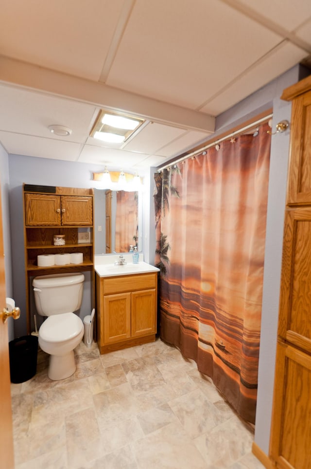 bathroom featuring vanity, toilet, curtained shower, and a paneled ceiling