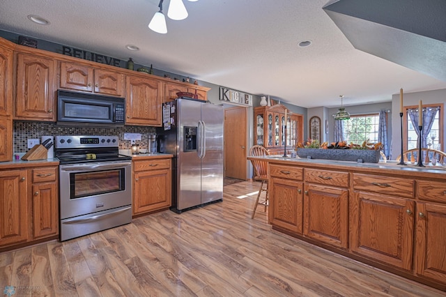429 Bridge Ave, Warren, MN 56762 - kitchen with stainless steel appliances, brown cabinets, light wood-style floors, a textured ceiling, and recessed lighting