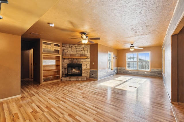 63219 Great River Rd, Jacobson, MN 55752 - unfurnished living room with a fireplace, a textured ceiling, light wood-type flooring, and ceiling fan