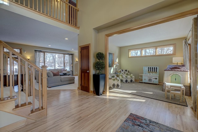 entrance foyer featuring a towering ceiling and light wood-type flooring