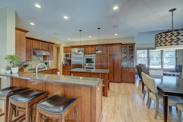 kitchen featuring a kitchen bar, decorative light fixtures, kitchen peninsula, light stone countertops, and backsplash