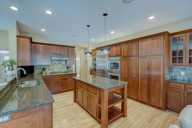 kitchen featuring pendant lighting, sink, appliances with stainless steel finishes, dark stone countertops, and a kitchen island