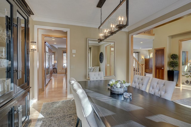 dining area featuring crown molding, an inviting chandelier, and light hardwood / wood-style flooring