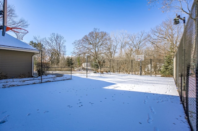 yard layered in snow featuring basketball court