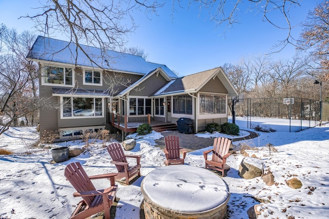 snow covered property with a wooden deck and a sunroom