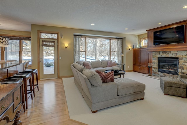 living room with plenty of natural light, light wood-type flooring, a textured ceiling, and a fireplace