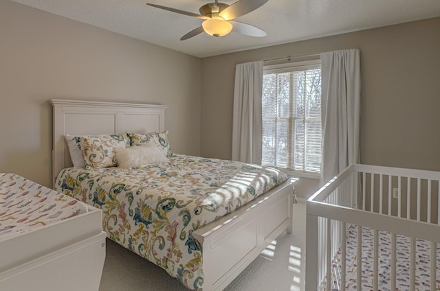 bedroom featuring a textured ceiling, light colored carpet, and ceiling fan