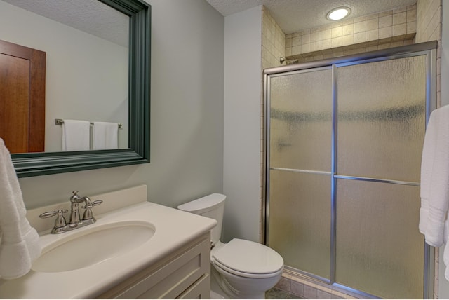 bathroom with vanity, a shower with shower door, toilet, and a textured ceiling