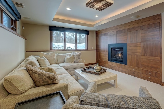 carpeted living room with a tiled fireplace and a raised ceiling