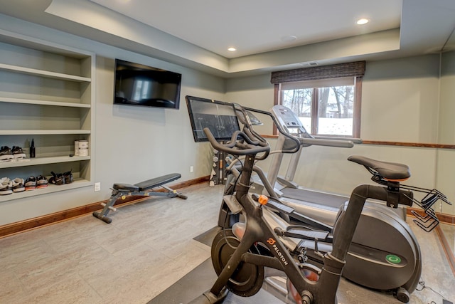 exercise room featuring a tray ceiling and built in features