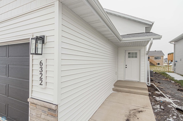 property entrance with central AC unit and a garage