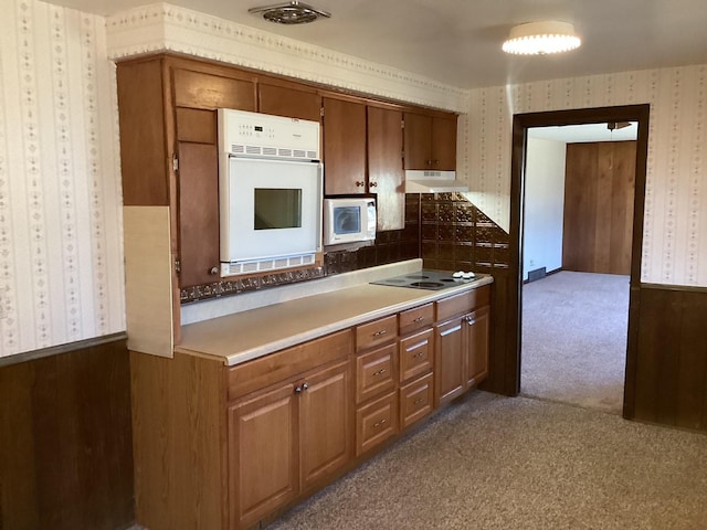 kitchen featuring white appliances, carpet floors, and wood walls