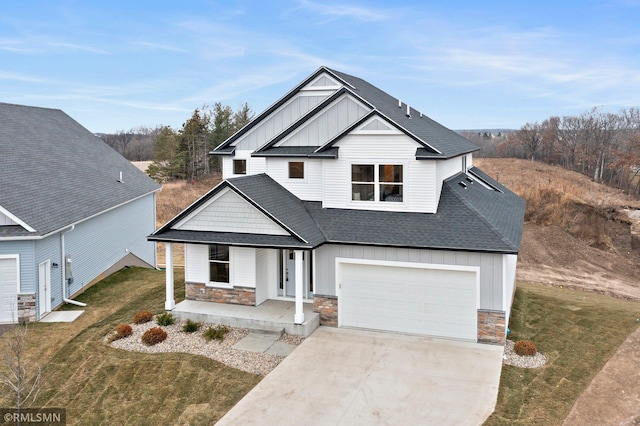 view of front of property featuring covered porch, a garage, and a front yard