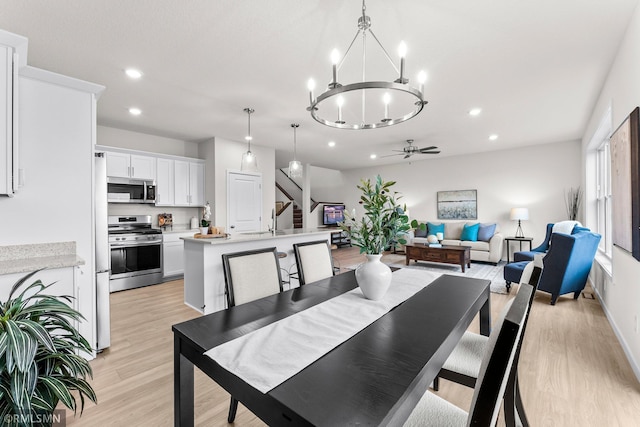 dining space with ceiling fan with notable chandelier and light wood-type flooring