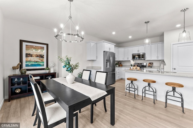 dining room featuring sink, a notable chandelier, and light wood-type flooring