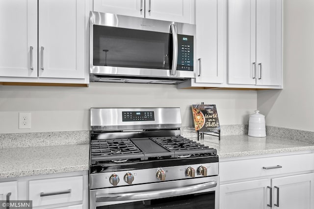 kitchen with white cabinets, stainless steel appliances, and light stone counters