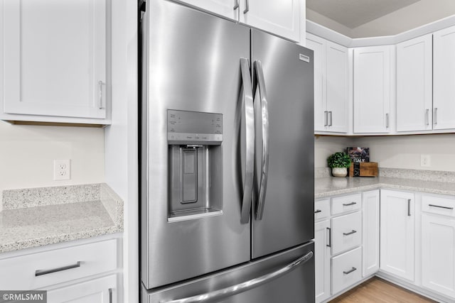 kitchen with light hardwood / wood-style floors, white cabinetry, light stone countertops, and stainless steel fridge with ice dispenser