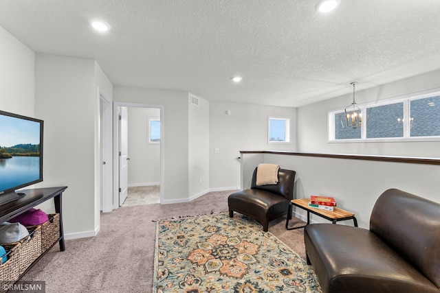 sitting room featuring a textured ceiling, light colored carpet, and a notable chandelier