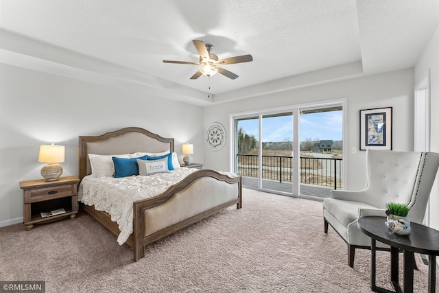 carpeted bedroom featuring a raised ceiling, ceiling fan, access to exterior, and a textured ceiling