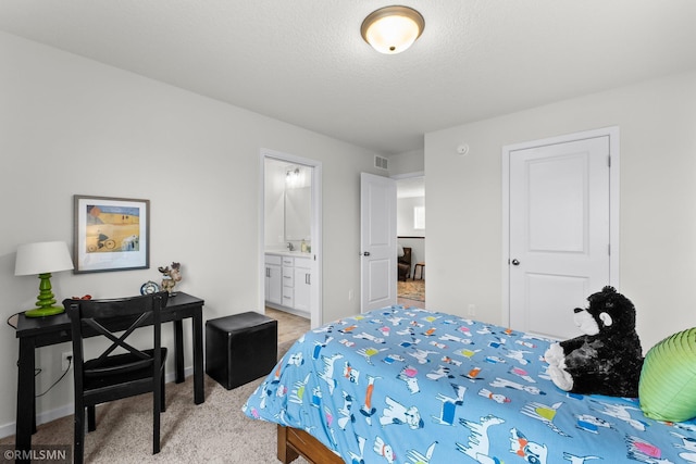 bedroom featuring ensuite bathroom, light colored carpet, and a textured ceiling