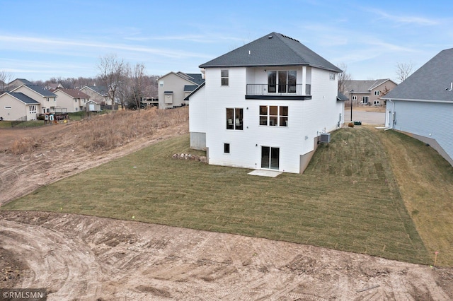 rear view of house featuring a yard, a balcony, and central AC