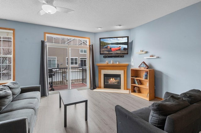 living room with ceiling fan, light hardwood / wood-style flooring, and a textured ceiling