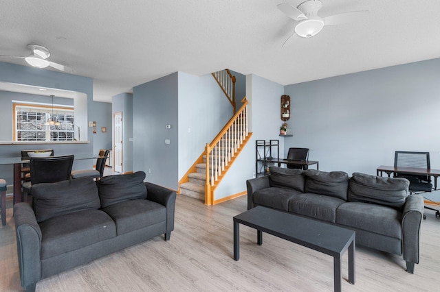 living room with ceiling fan, a textured ceiling, and light wood-type flooring