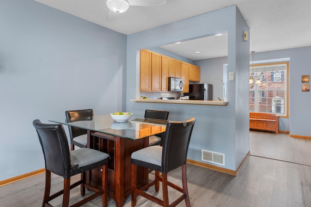 dining area featuring ceiling fan with notable chandelier and light hardwood / wood-style floors