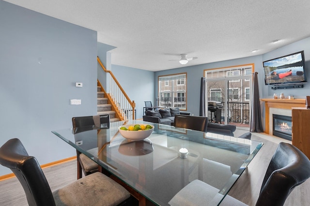 dining space featuring ceiling fan, a textured ceiling, and light hardwood / wood-style floors