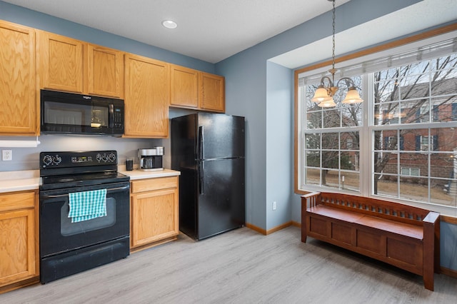 kitchen featuring decorative light fixtures, black appliances, a chandelier, and light wood-type flooring