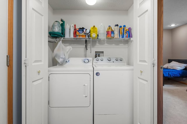 washroom featuring carpet floors, washing machine and clothes dryer, and a textured ceiling