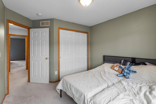 carpeted bedroom with a closet and a textured ceiling