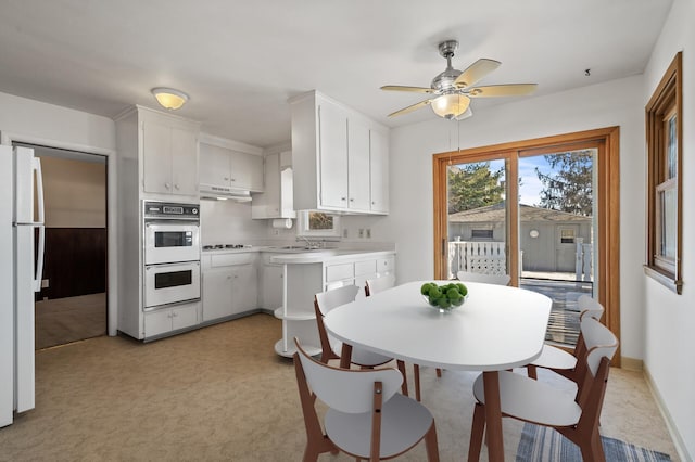 kitchen with ceiling fan, sink, white cabinets, light colored carpet, and white appliances